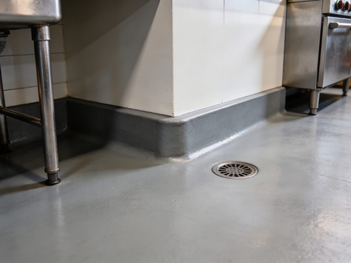 A commercial kitchen floor in seamless urethane cement with a coved base and a floor drain
